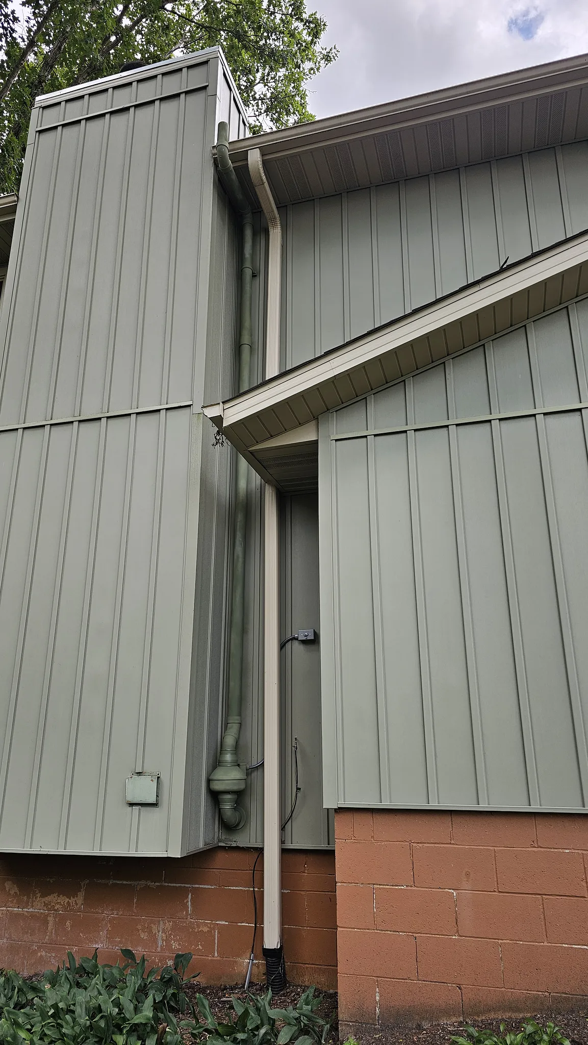 Radon mitigation pipe run, painted to blend with green siding